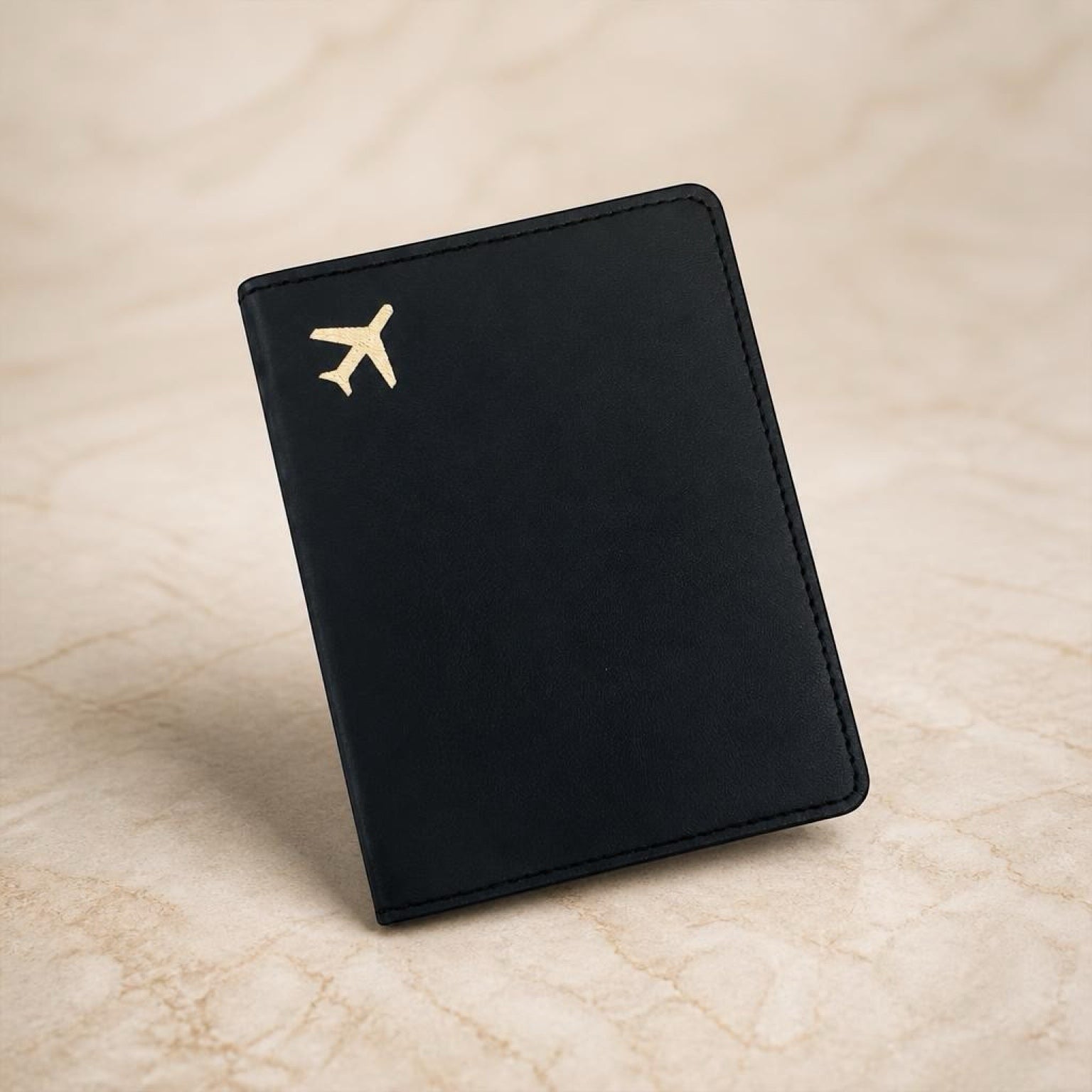 Chévereh black PU leather passport holder with a minimalist gold airplane emblem for travel organization.