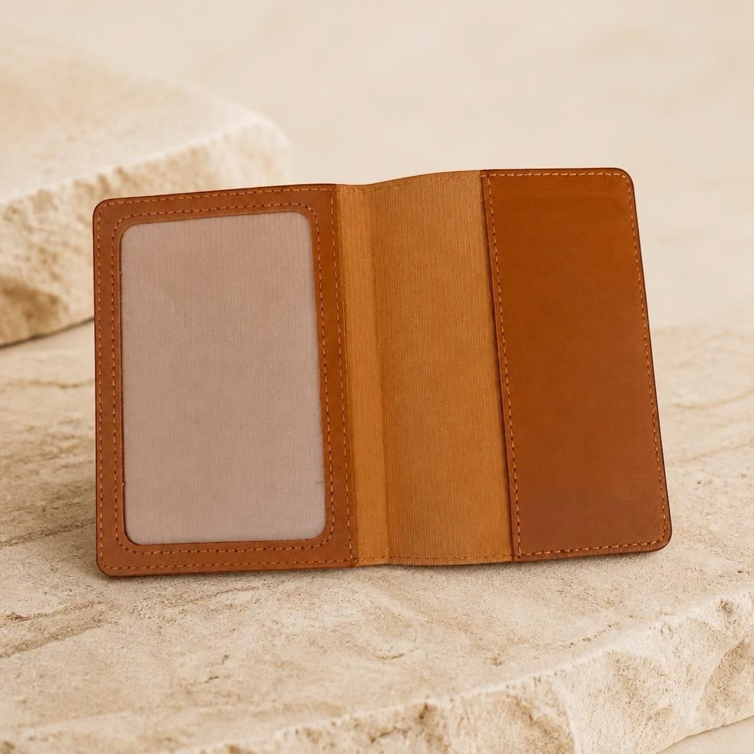 Chévereh brown PU leather passport holder with clear ID window and card slots on a textured stone surface.