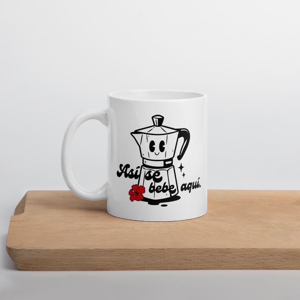Chévereh Ceramic Mug 11oz with a smiling coffee maker, hibiscus flower, and "Así se bebe aquí" text.