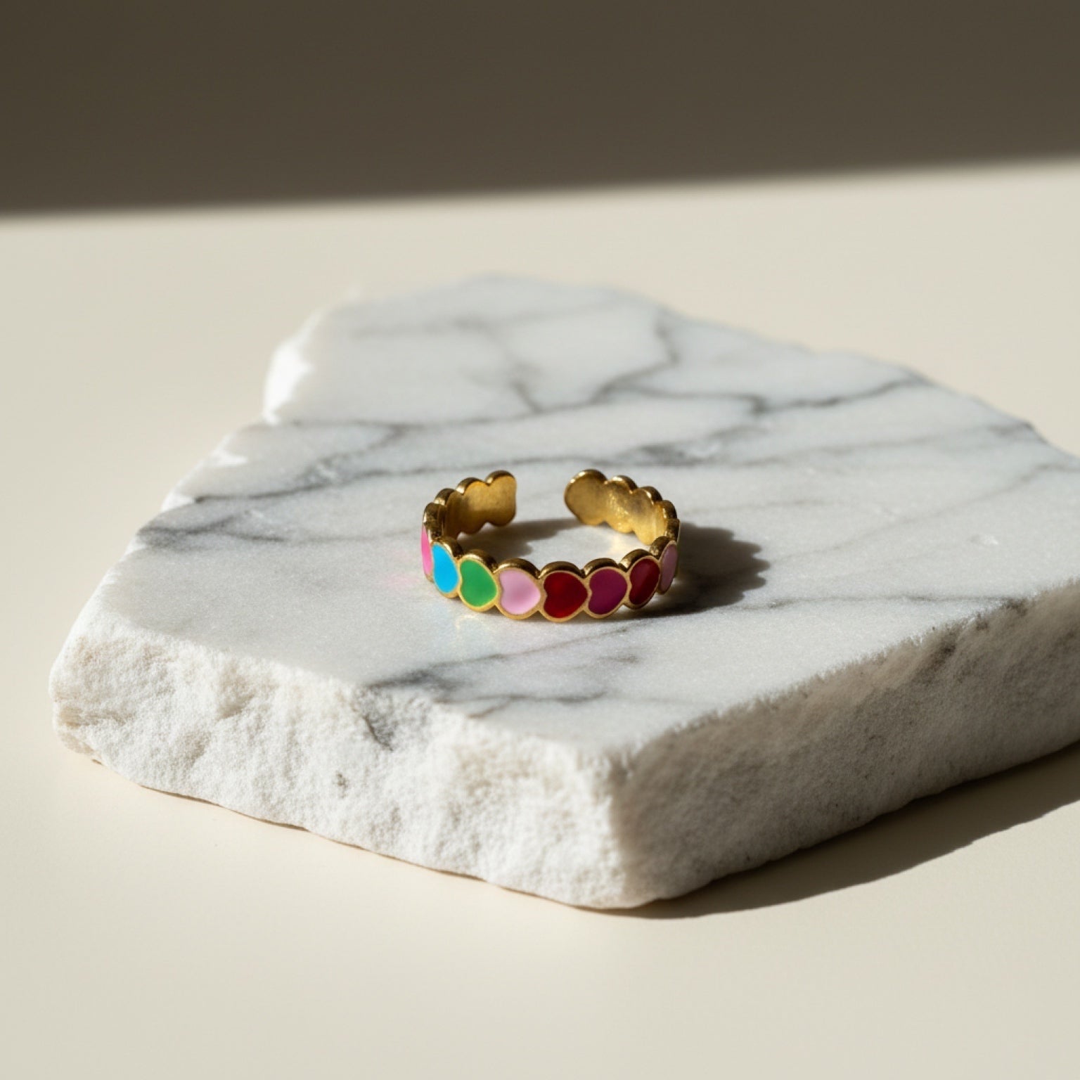 Chévereh gold-tone adjustable ring with colorful enameled hearts in pink, blue, green, and red.