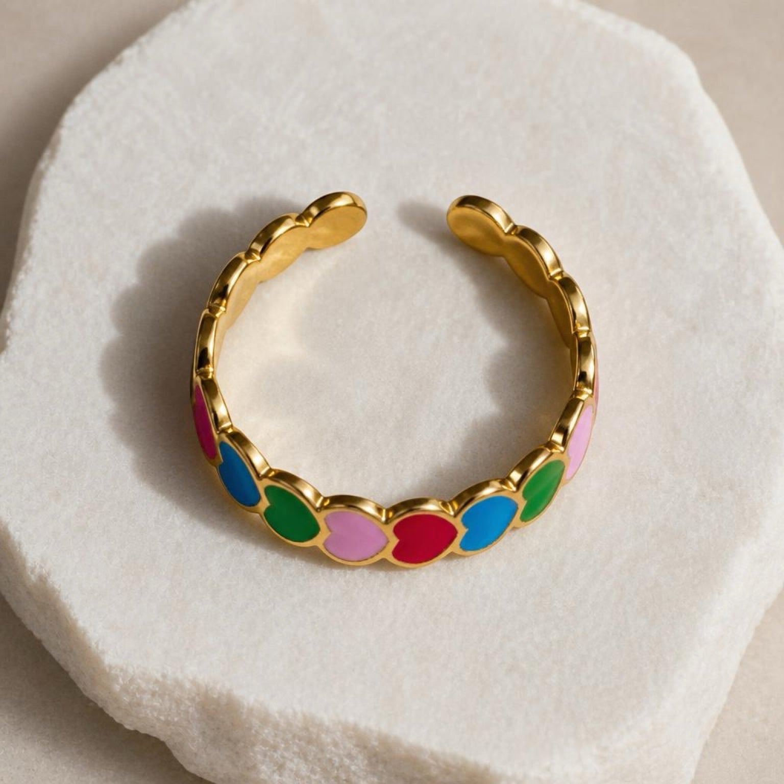 Chévereh gold-tone adjustable ring with colorful enameled hearts in pink, blue, green, and red.