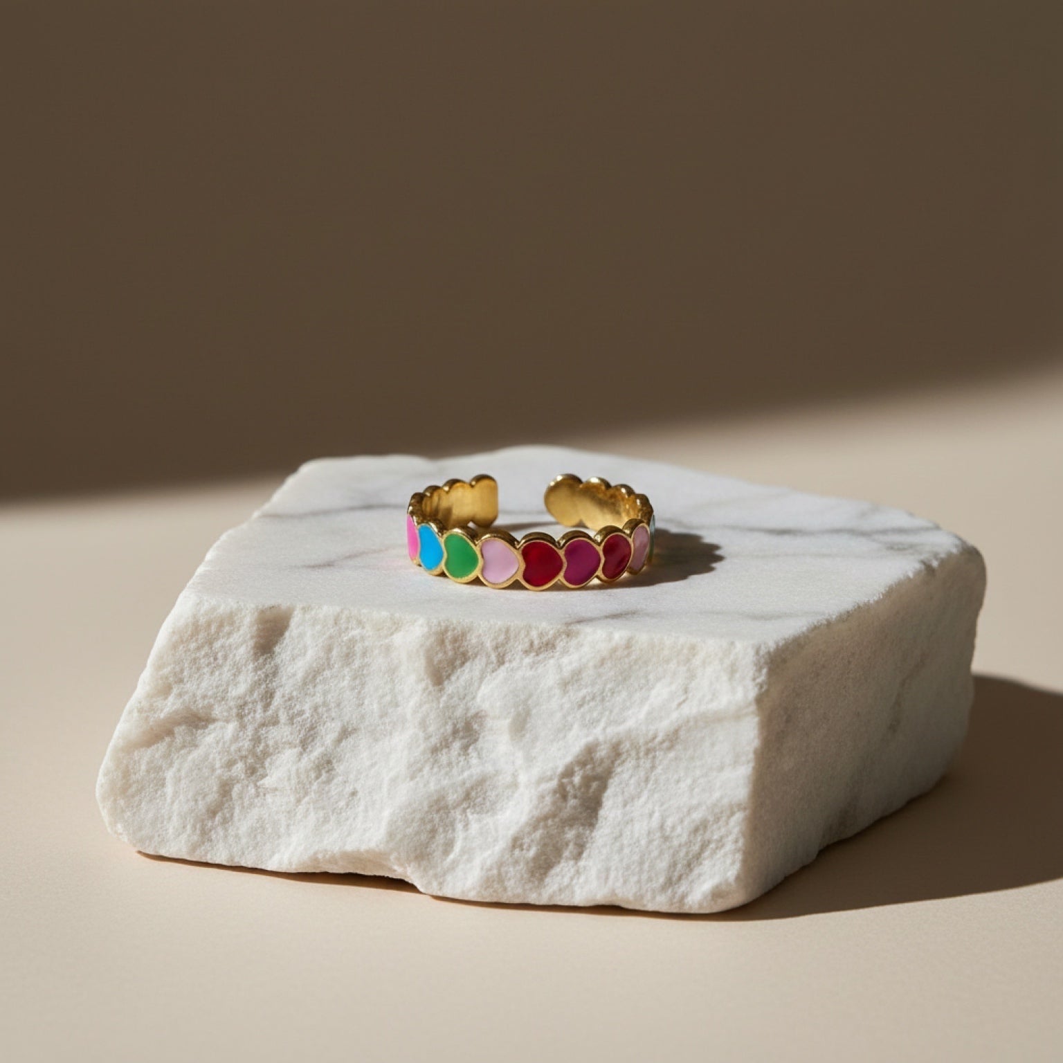 Chévereh gold-tone adjustable ring with colorful enameled hearts in pink, blue, green, and red.