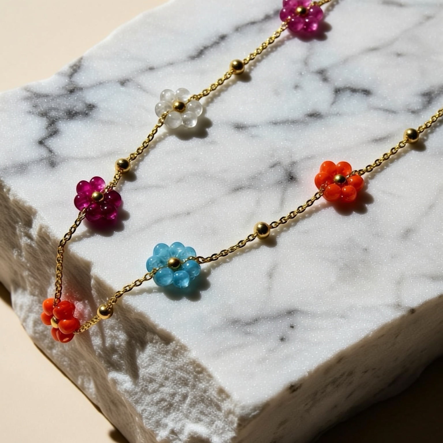 Chévereh gold-tone chain necklace with colorful floral beaded charms and gold spheres. Features pink, clear, blue, and orange flower beads.