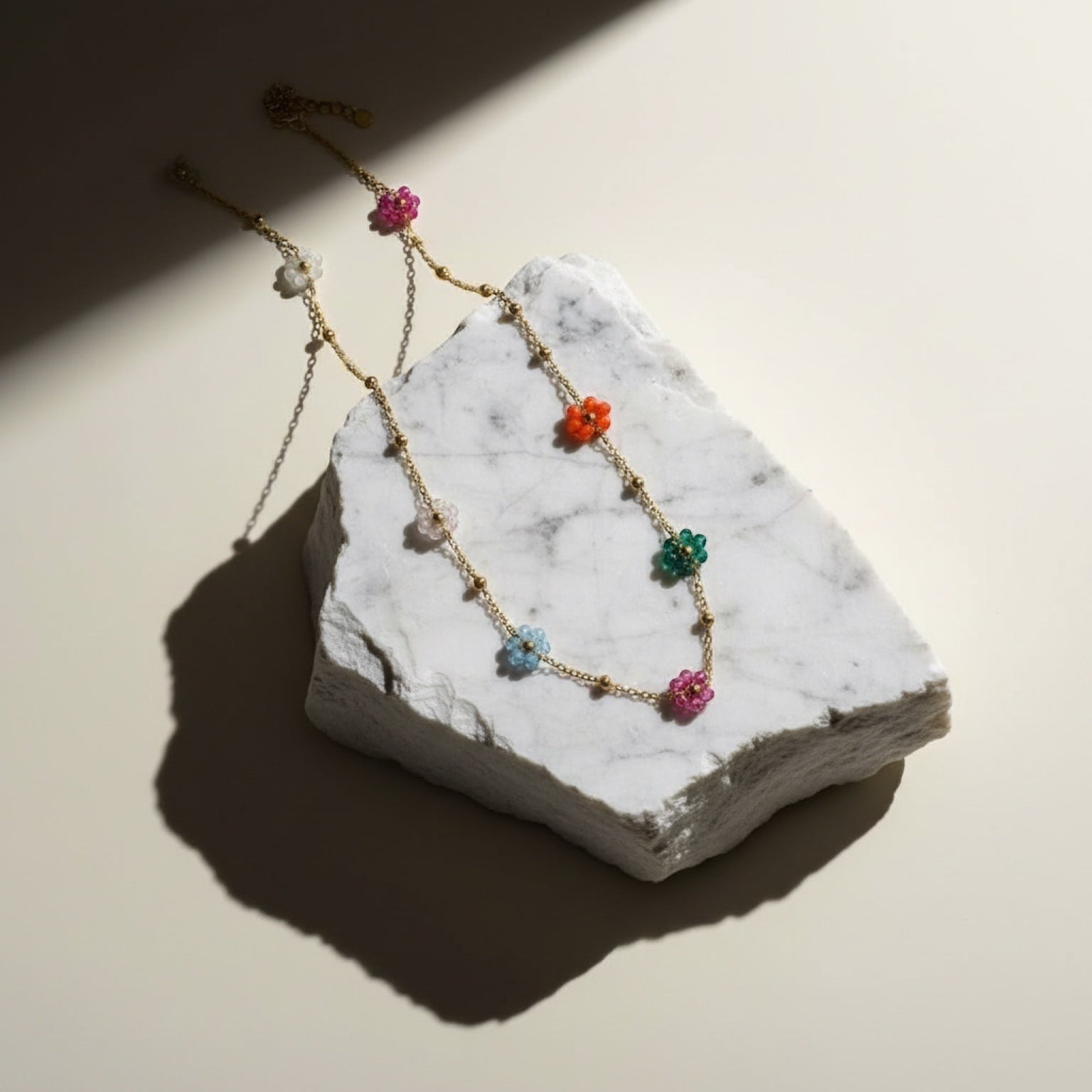 Chévereh gold-tone chain necklace with colorful floral beads in pink, blue, green, and orange, accented with small gold spheres.