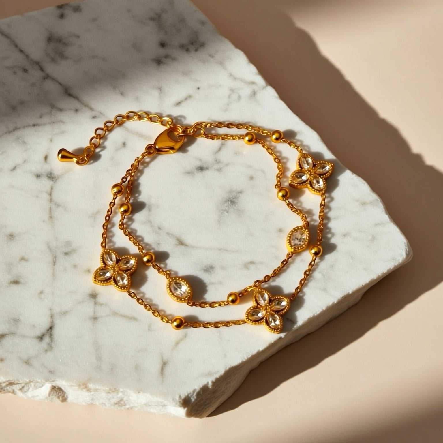 Chévereh gold double-chain bracelet with sparkling crystal four-leaf clover charms and bead accents.