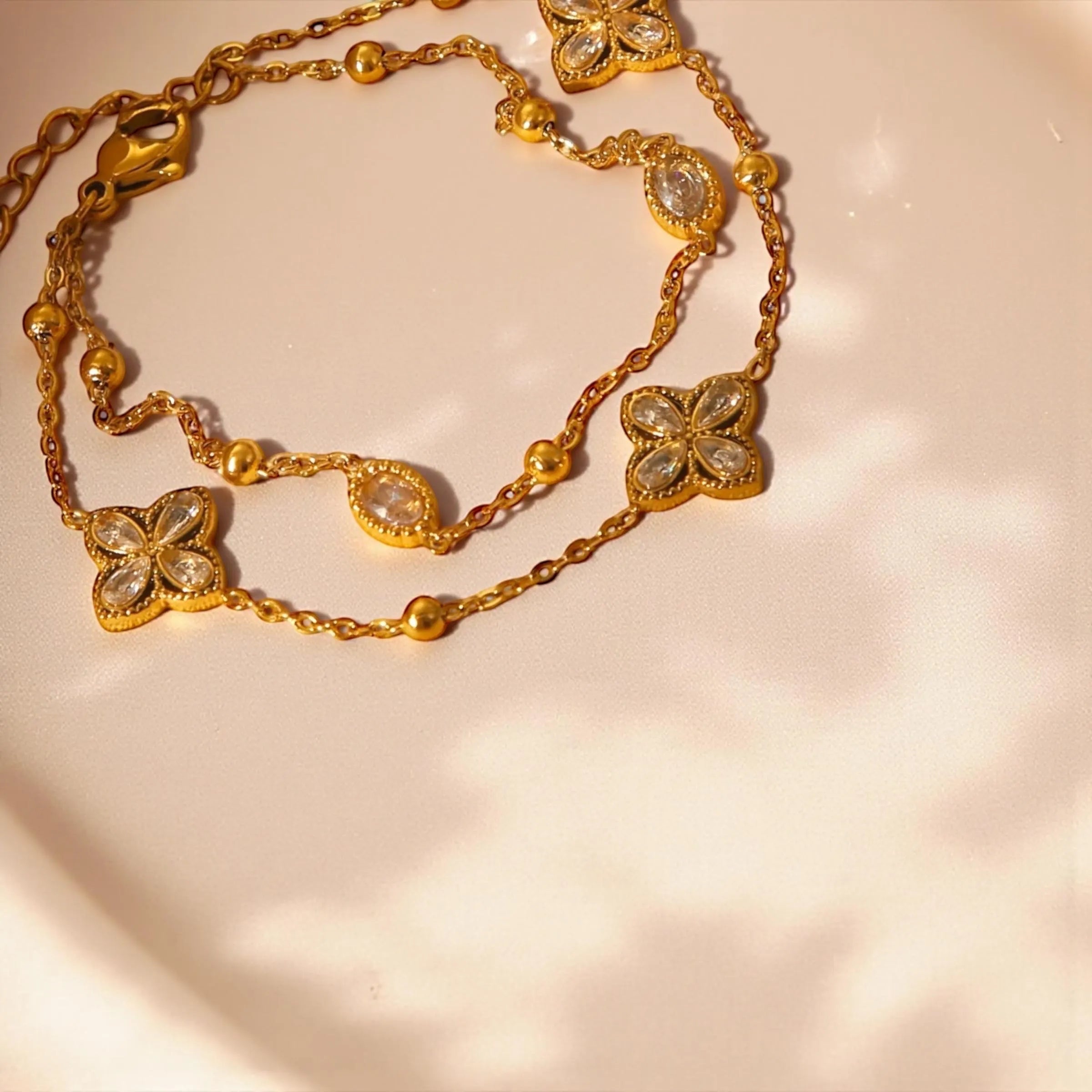 Chévereh gold double-chain bracelet with four-leaf clover charms and clear crystals. Made from 304 stainless steel.