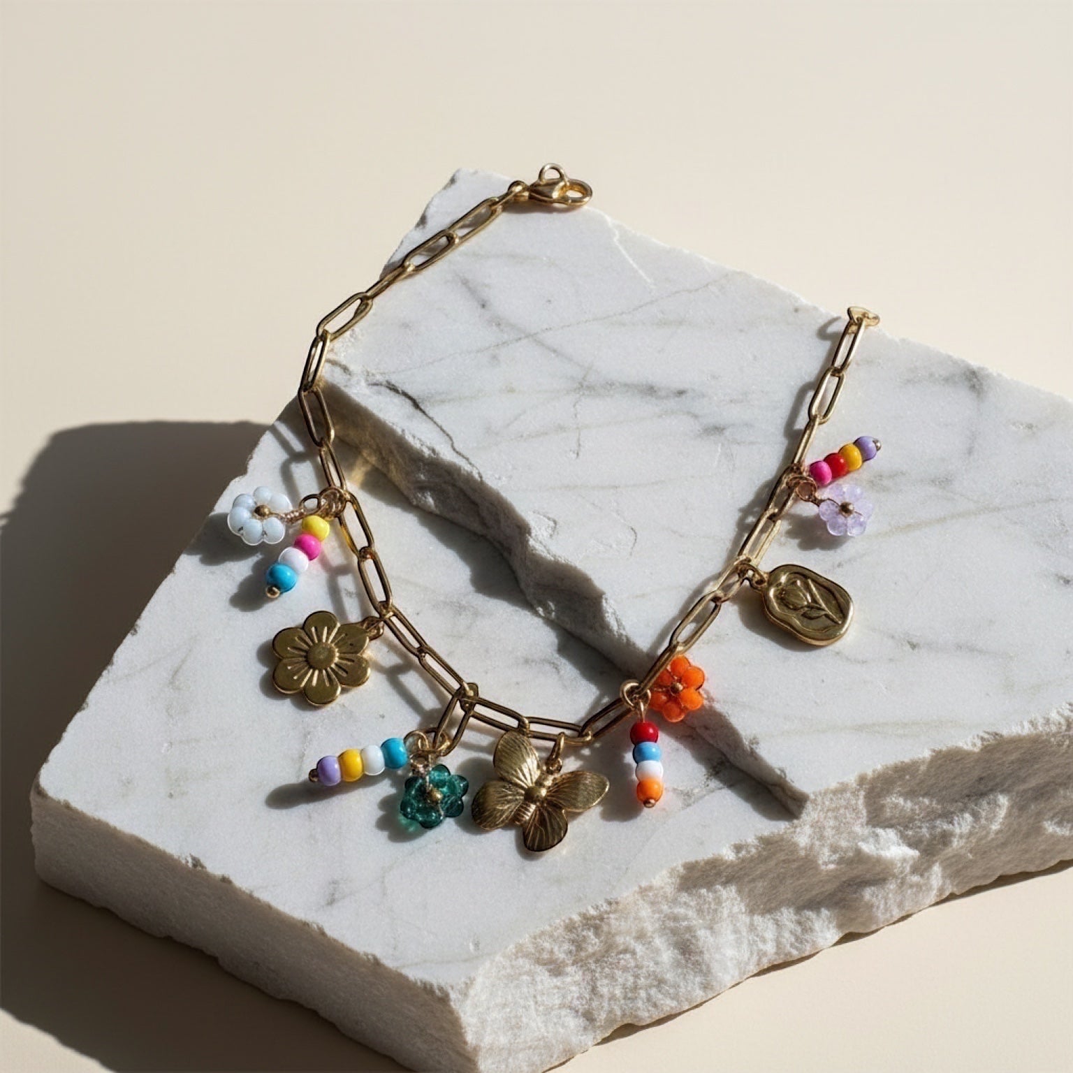 Chévereh gold-tone paperclip chain necklace with flower, butterfly, and colorful beaded charms.