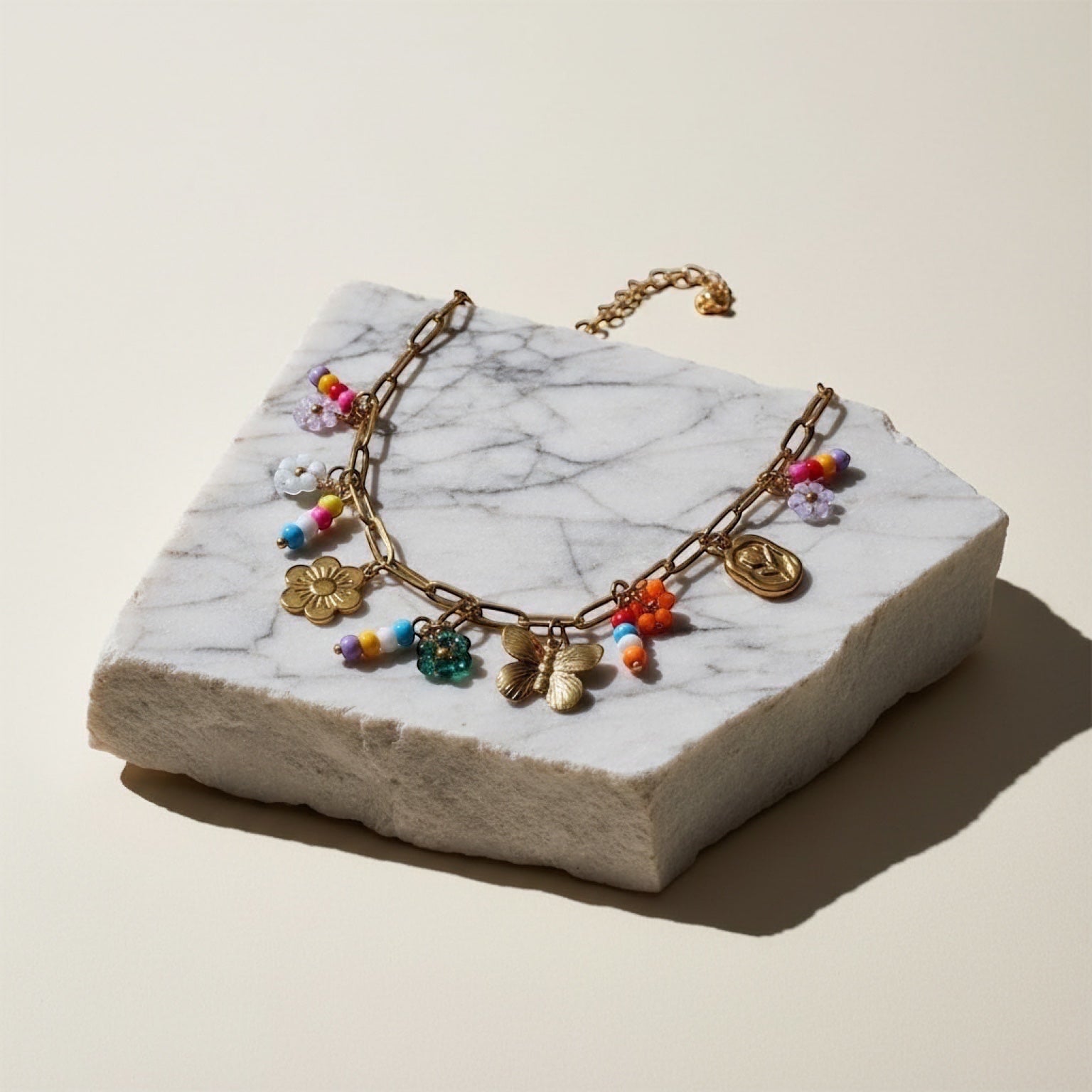 Chévereh gold-tone paperclip chain necklace with flower, butterfly, and colorful beaded charms.