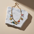 Chévereh gold-tone paperclip chain necklace with flower, butterfly, and colorful beaded charms.