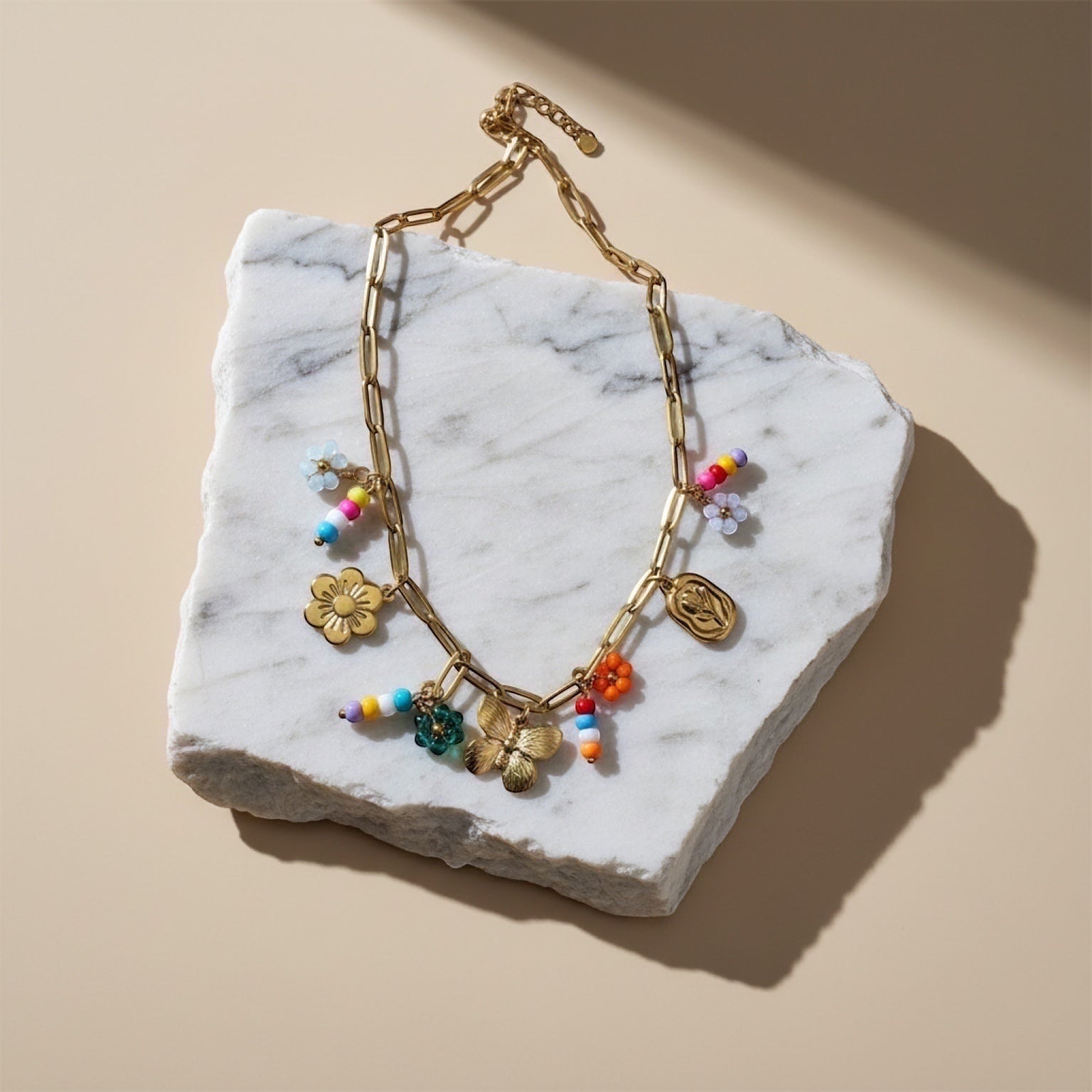 Chévereh gold-tone paperclip chain necklace with flower, butterfly, and colorful beaded charms.