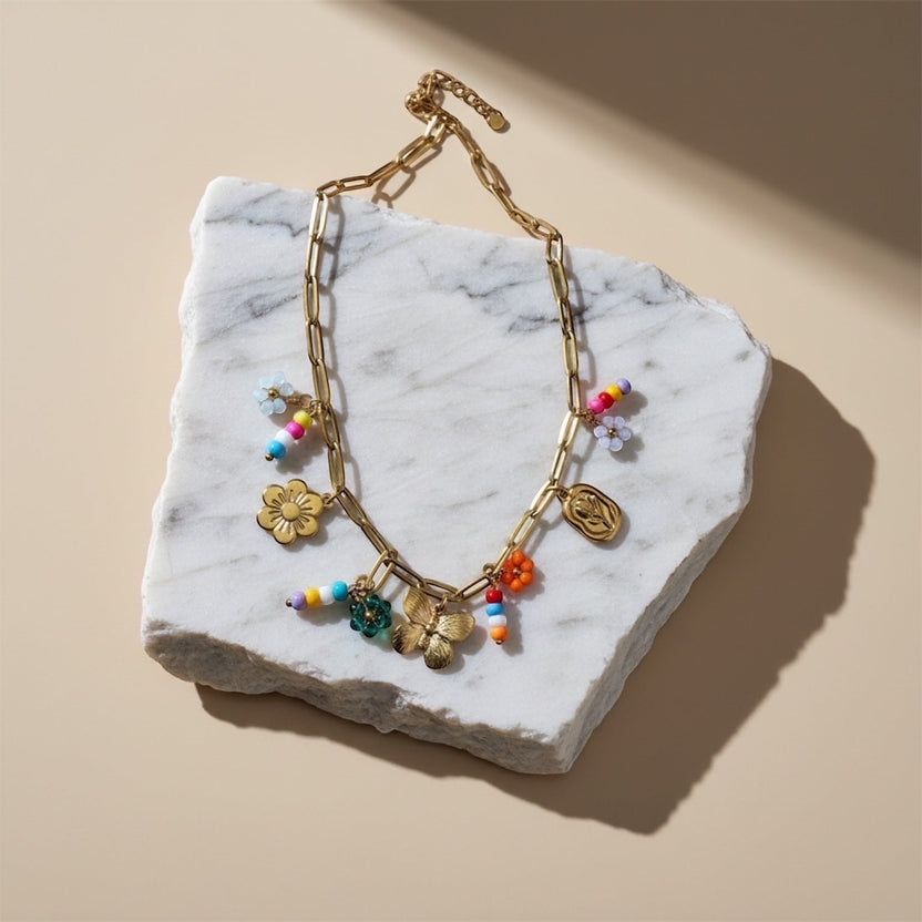 Chévereh gold-tone paperclip chain necklace with flower, butterfly, and colorful beaded charms.