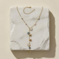 Chévereh gold-tone Y-necklace with faux pearls, white flower charms, blue butterflies, and polished gold hearts.