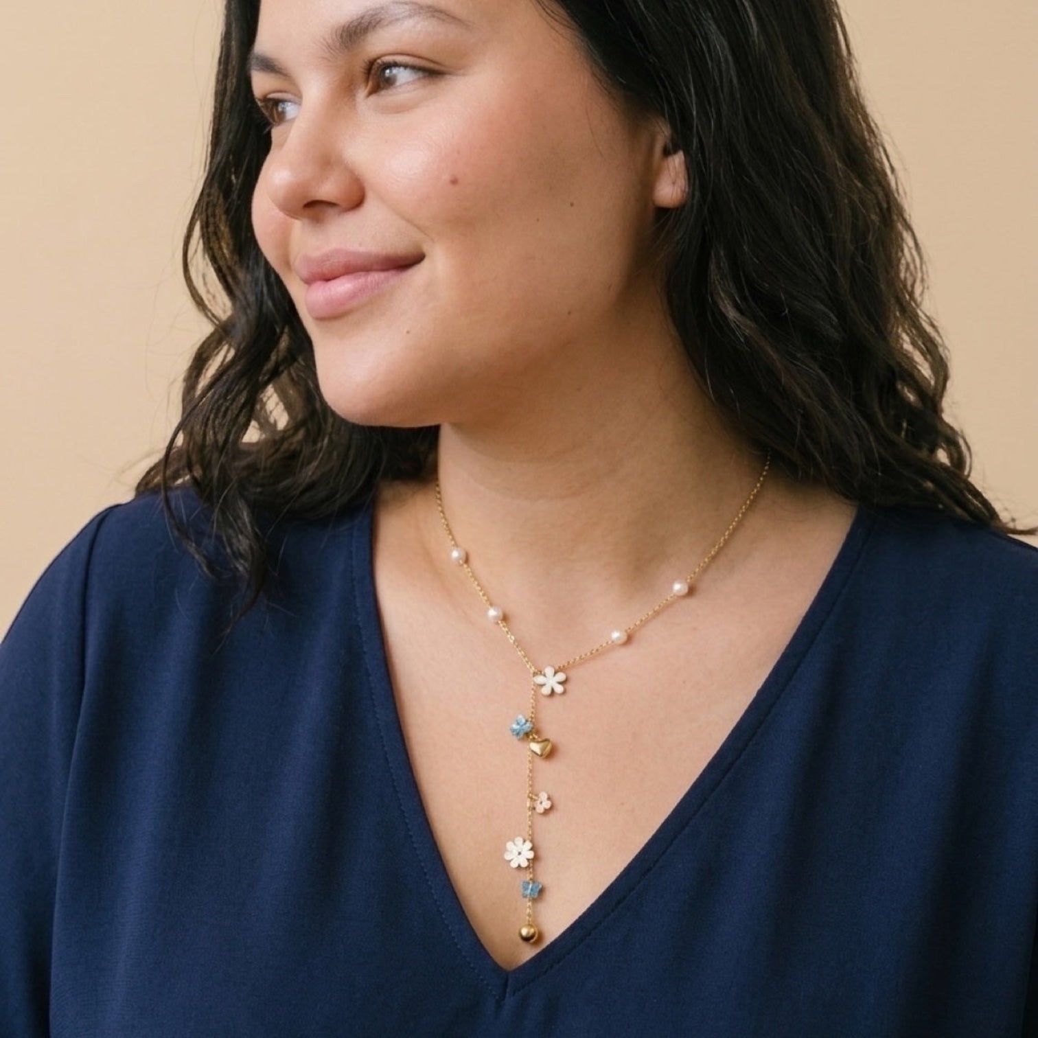 Chévereh gold-tone Y-necklace with faux pearls, white flower charms, blue butterflies, and gold hearts on a model.