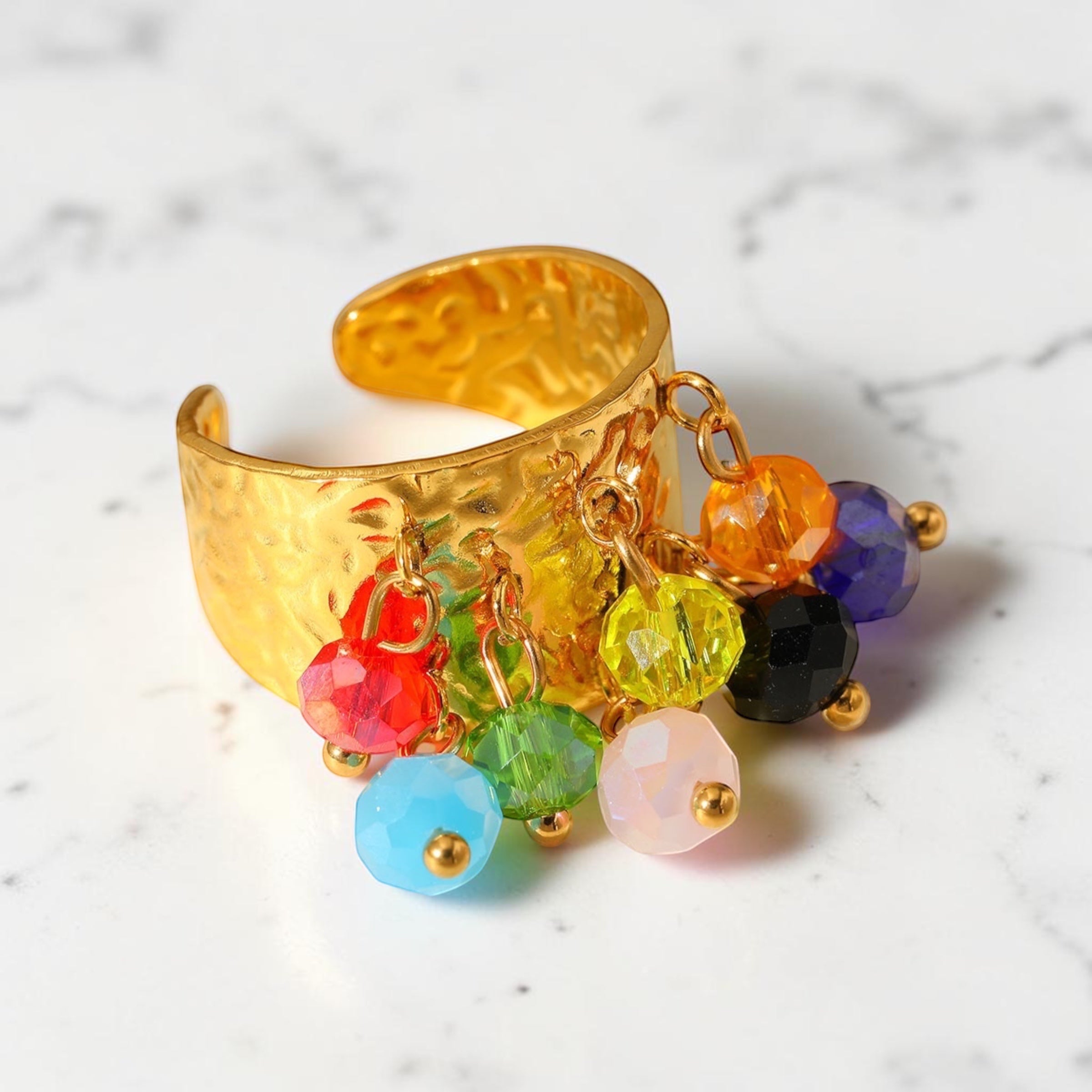 Chévereh gold-toned hammered metal statement ring with dangling multi-colored beaded charms on an adjustable band.