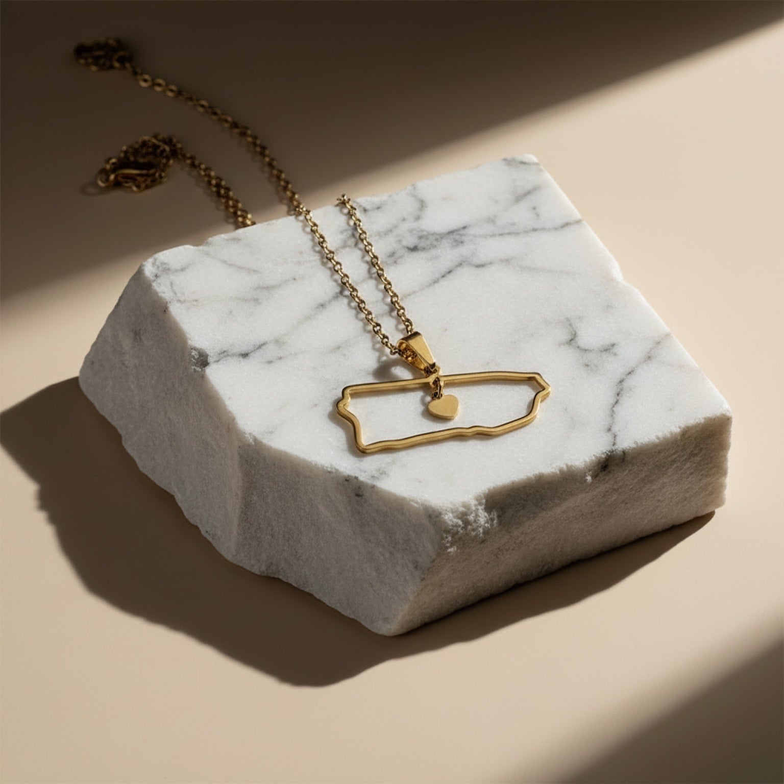 Chévereh gold-tone metal island outline pendant necklace with a small heart charm.