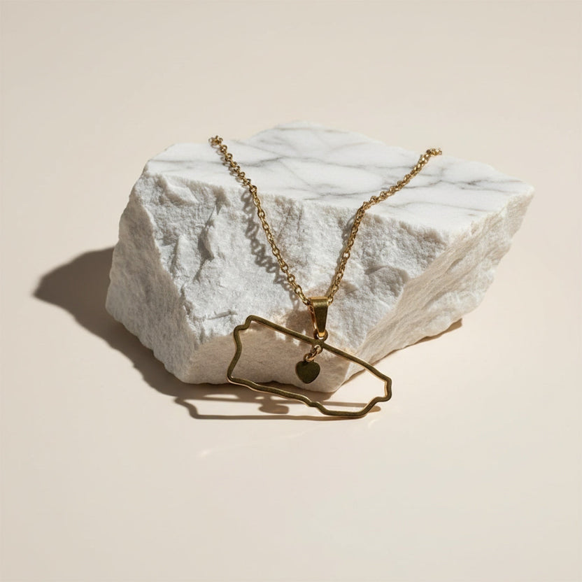 Chévereh gold-tone metal island outline pendant necklace with a small heart charm.