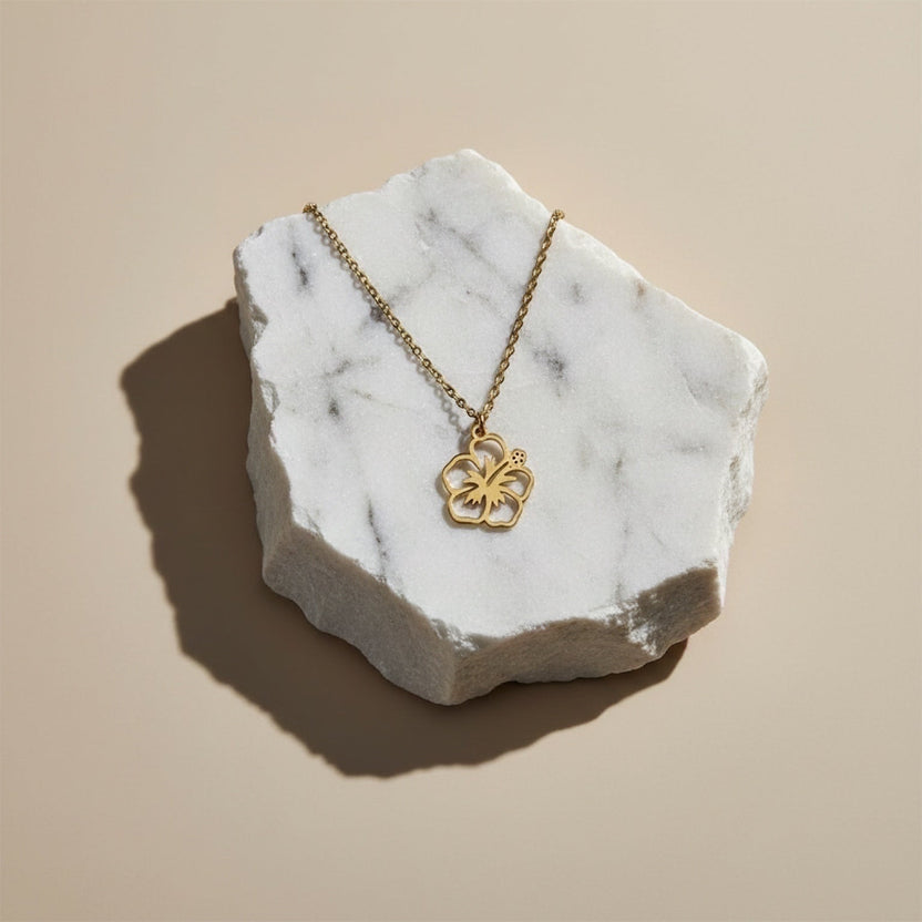 Chévereh gold-tone maga flower pendant necklace on a marble display.