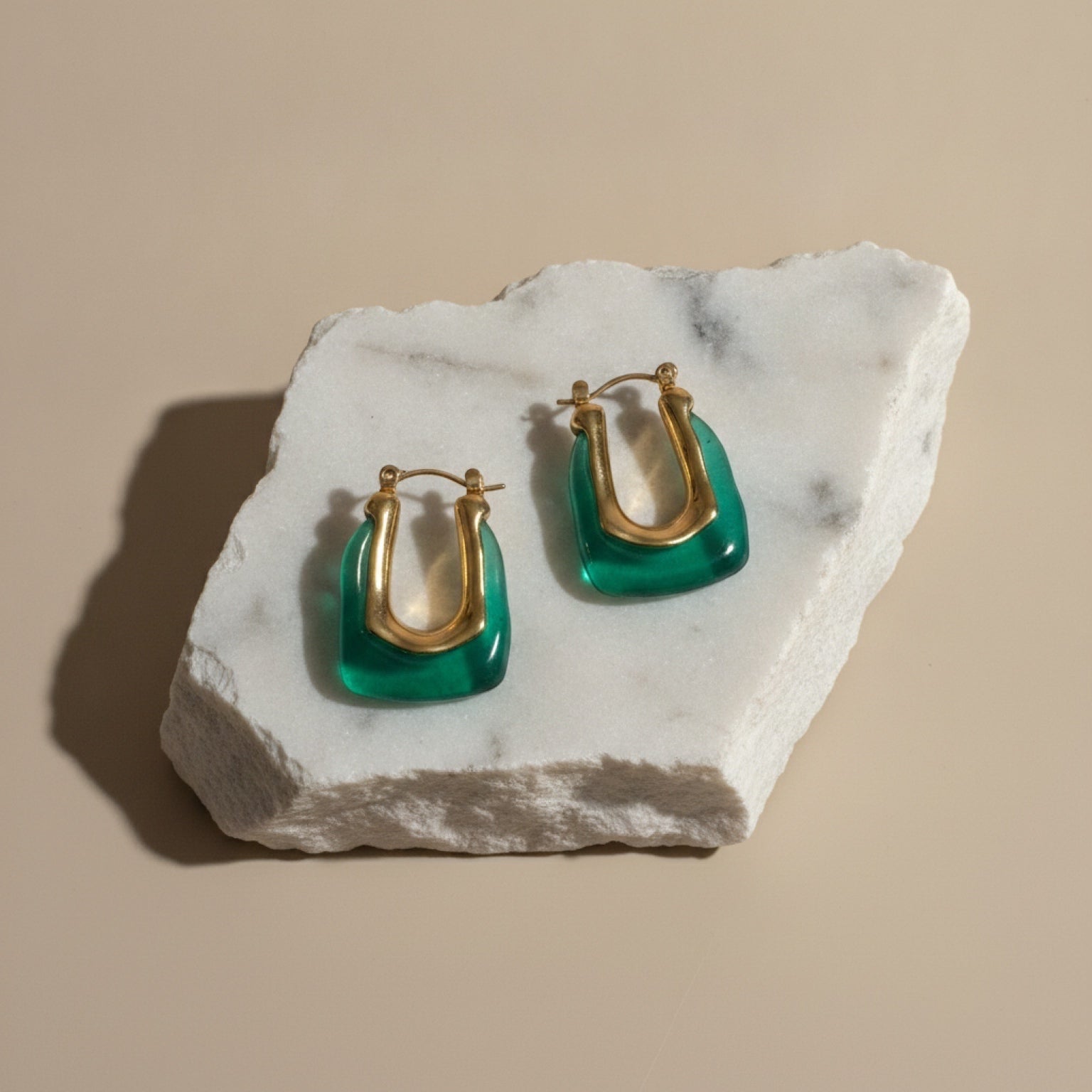 Chévereh sculptural hoop earrings featuring gold-tone stainless steel and translucent green resin on marble stone.