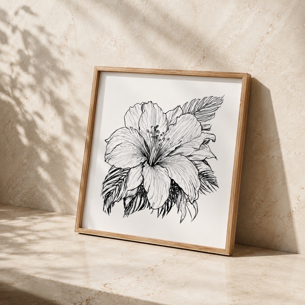 Chévereh tropical hibiscus flower line art print in a light wood frame leaning against a beige stone wall.