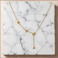 Chévereh gold-tone stainless steel Y-necklace featuring MAMA block letter pendants on a white marble background.