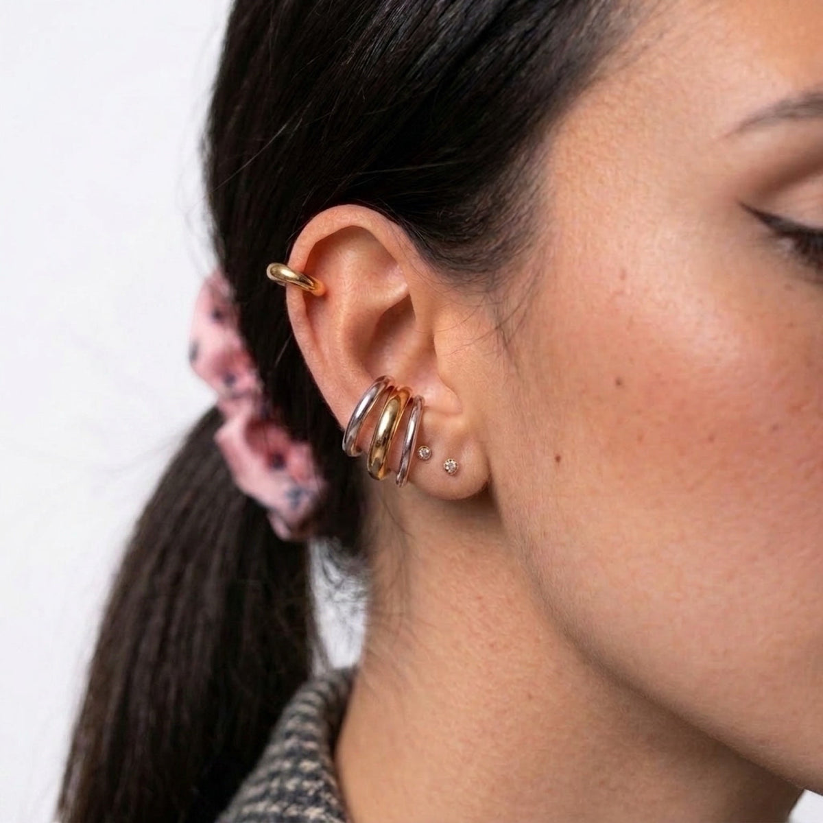 Chévereh minimalist ear cuffs in gold and silver tones stacked on a model's ear for a modern layered look.