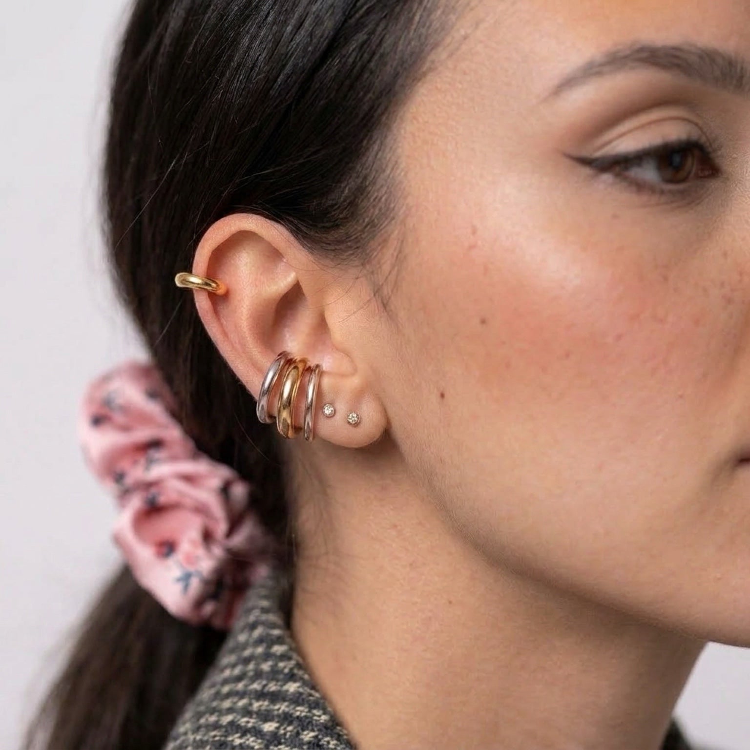 Chévereh minimalist ear cuffs in gold and silver tones stacked on a model's ear for a modern, polished look.