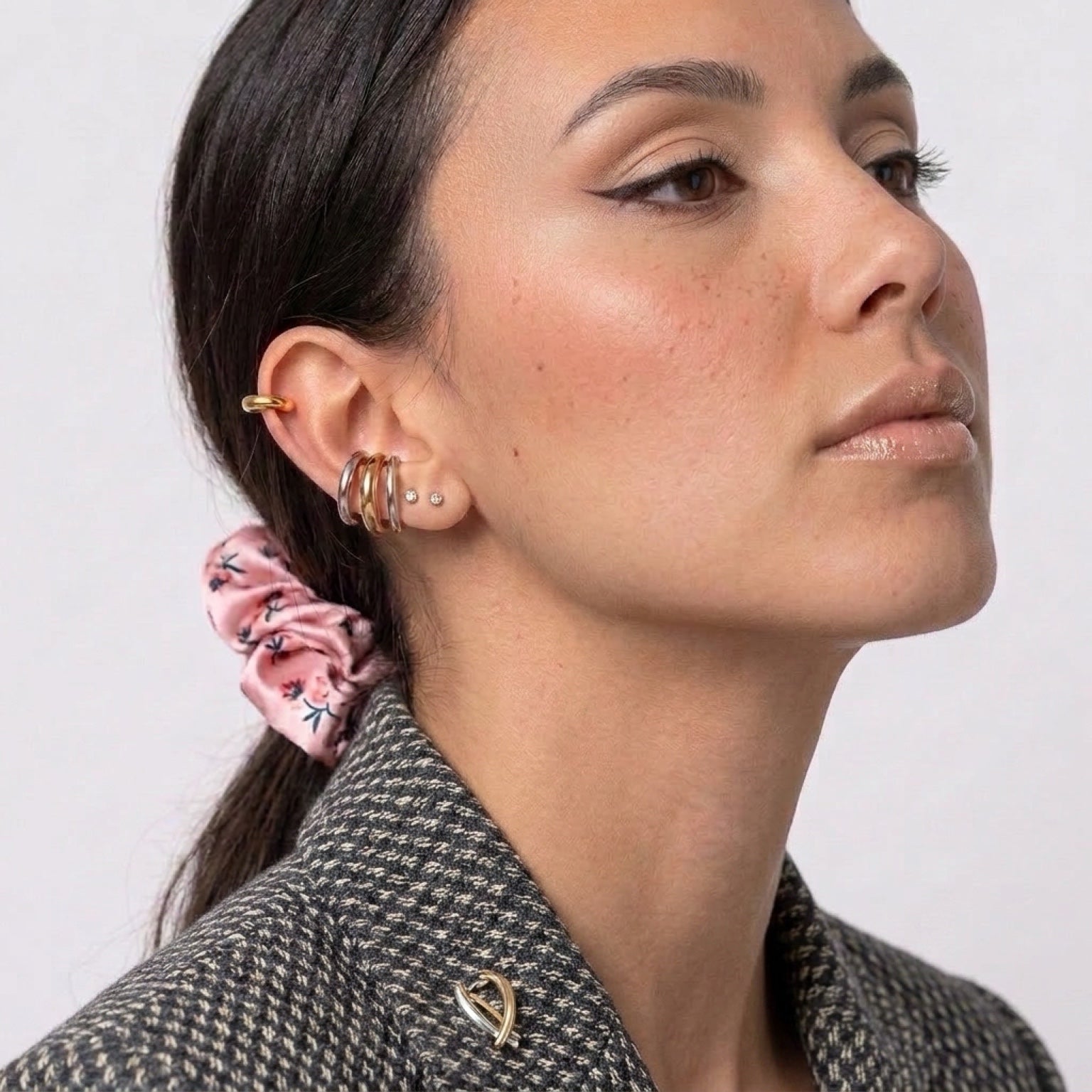 Chévereh minimalist gold and silver ear cuffs stacked on a model wearing a patterned blazer and pink floral scrunchie.