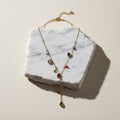Chévereh dainty gold-tone stainless steel drop necklace featuring colorful multifaceted stones on a marble display.