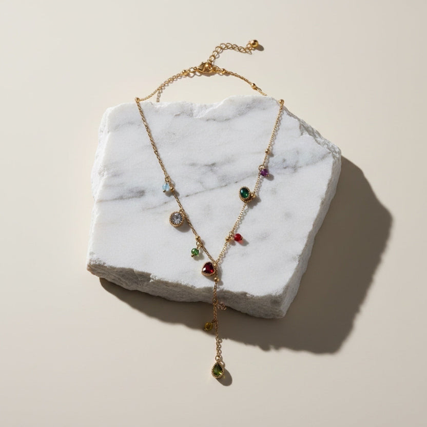 Chévereh dainty gold-tone stainless steel drop necklace featuring colorful multifaceted stones on a marble display.