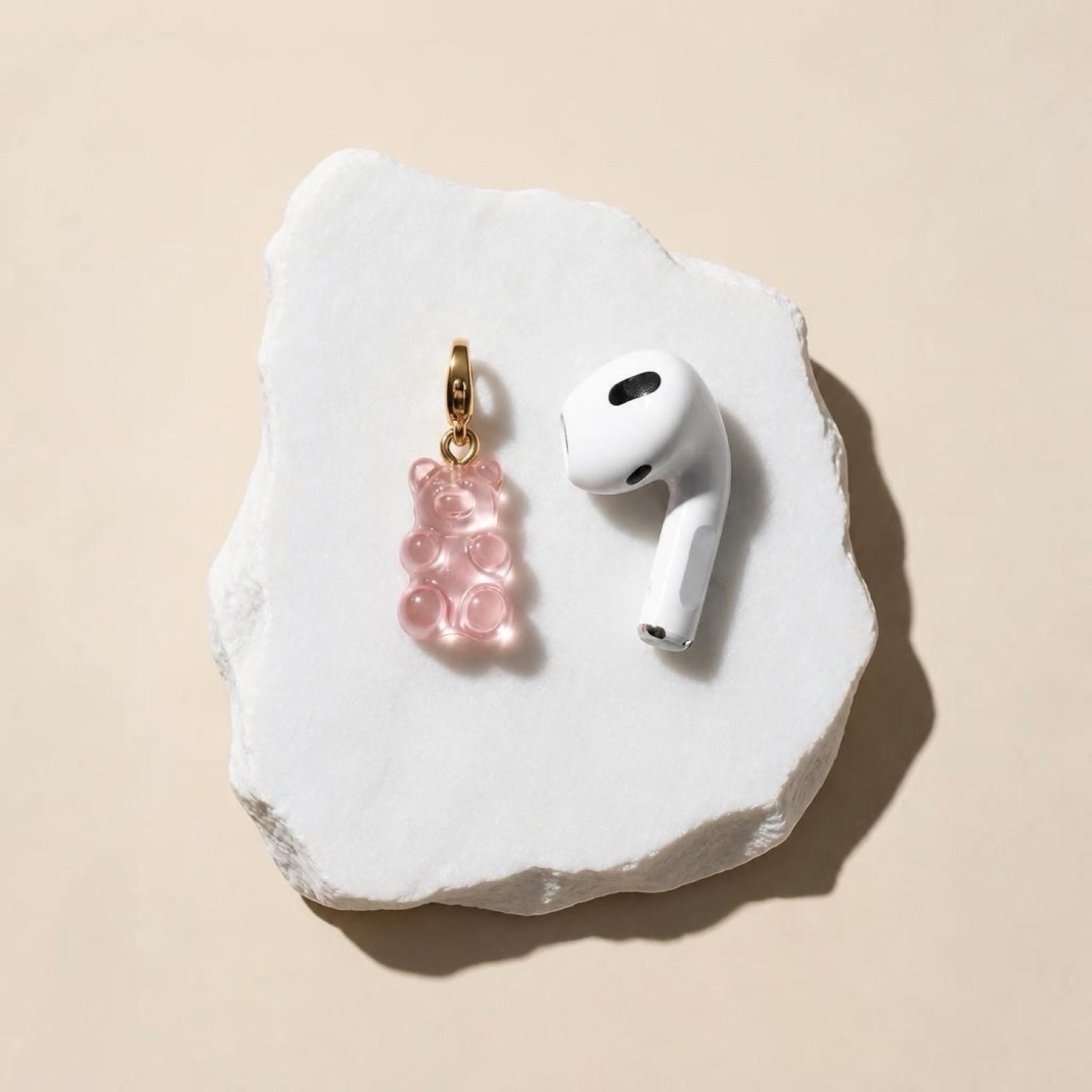 Chévereh translucent pink resin gummy bear charm with a gold-toned lobster clasp resting on a white stone surface.