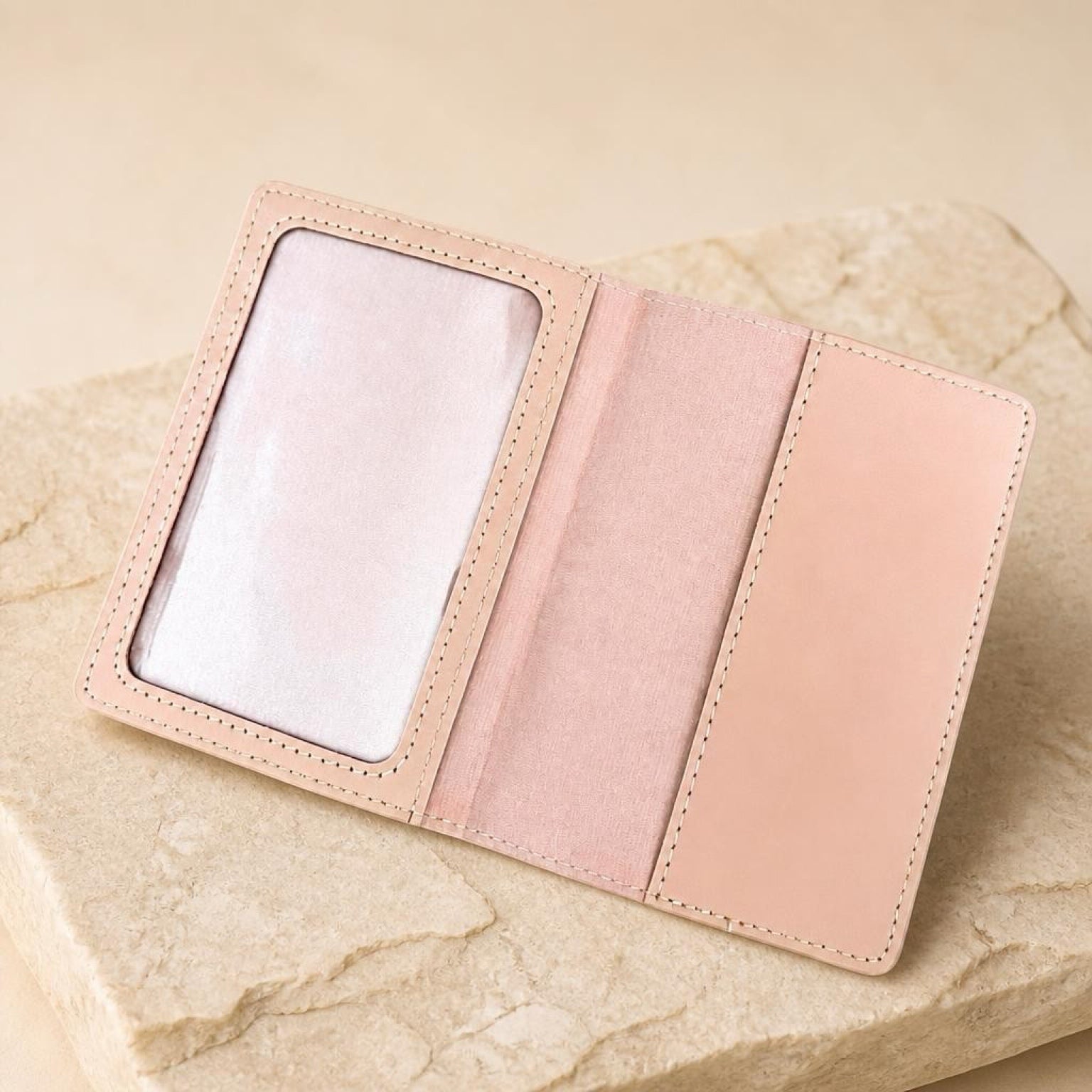Chévereh pink PU leather passport holder with clear ID window and card slots, displayed on a textured stone surface.