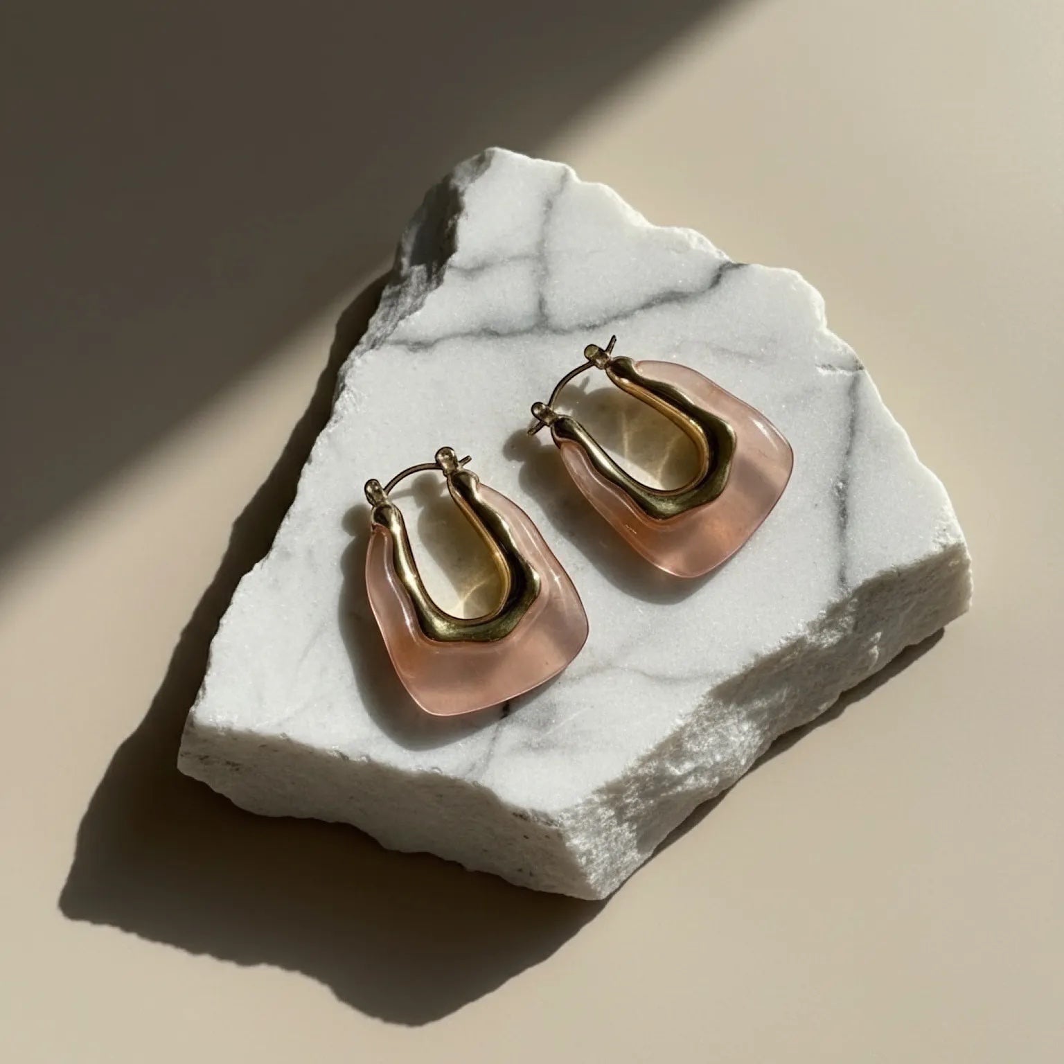 Chévereh blush pink resin and gold-tone sculptural hoop earrings with stainless steel posts.