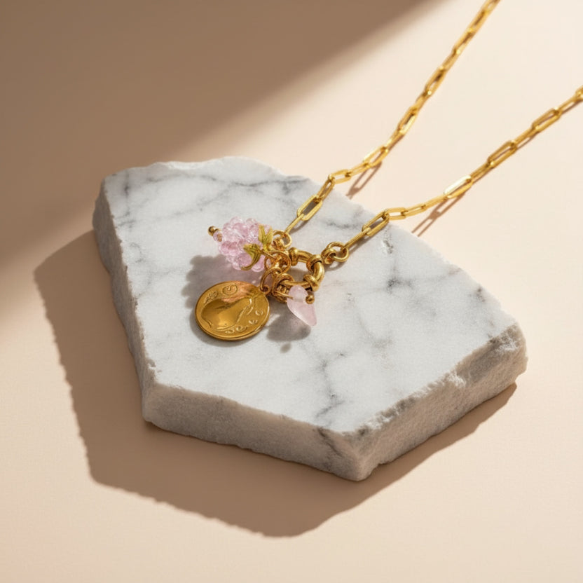 Chévereh Pinky Charm Necklace with gold chain, pink beads, gold coin, and rose quartz stone.