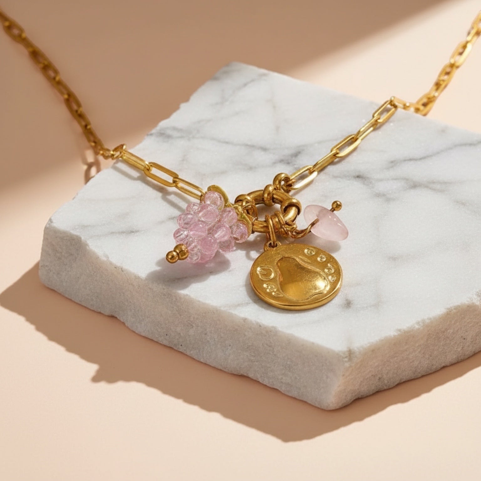 Chévereh Pinky Charm Necklace with gold chain, pink beaded cluster, gold coin, and rose quartz stone.