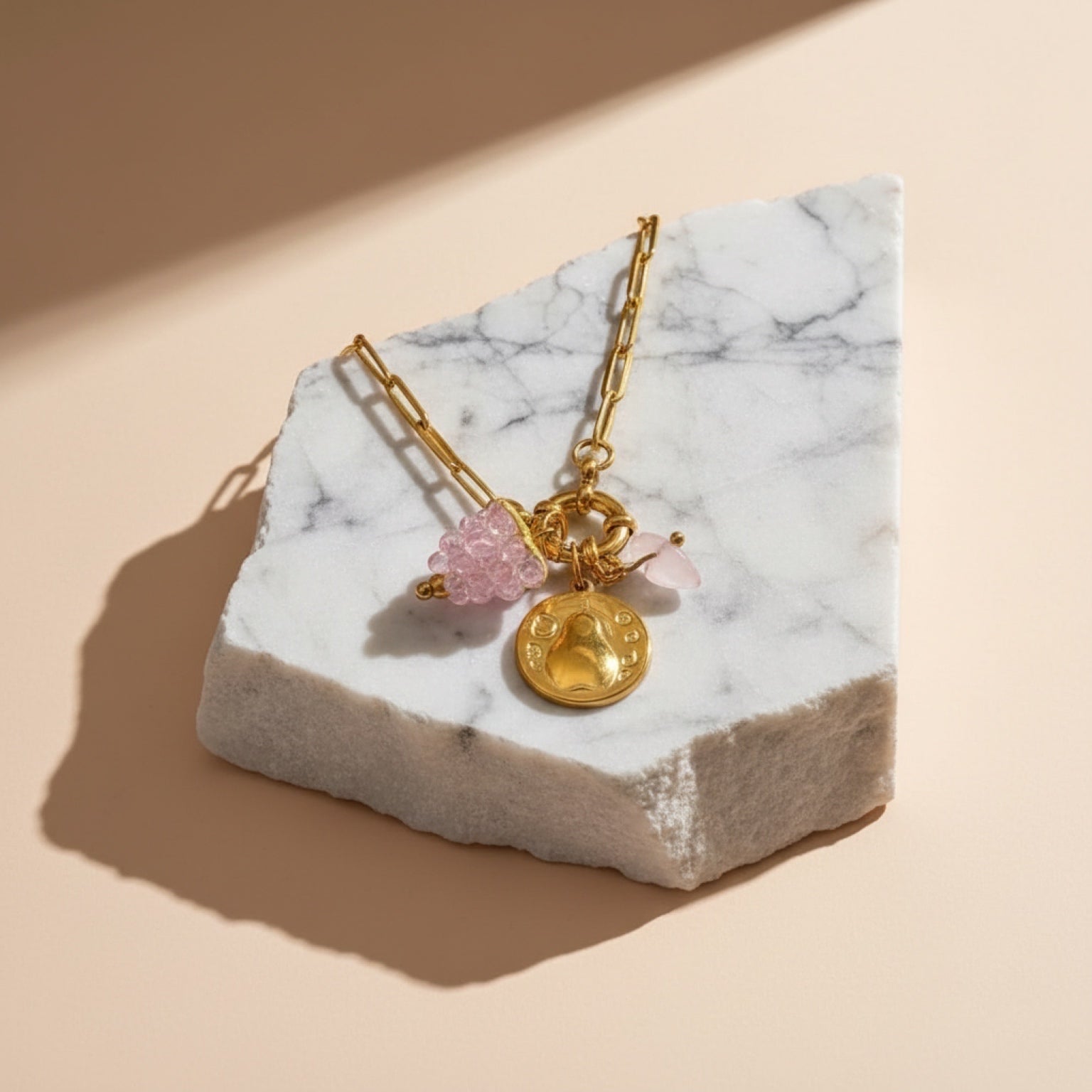 Chévereh Pinky Charm Necklace with gold-tone chain, pink beaded accent, gold coin charm, and rose quartz stone.