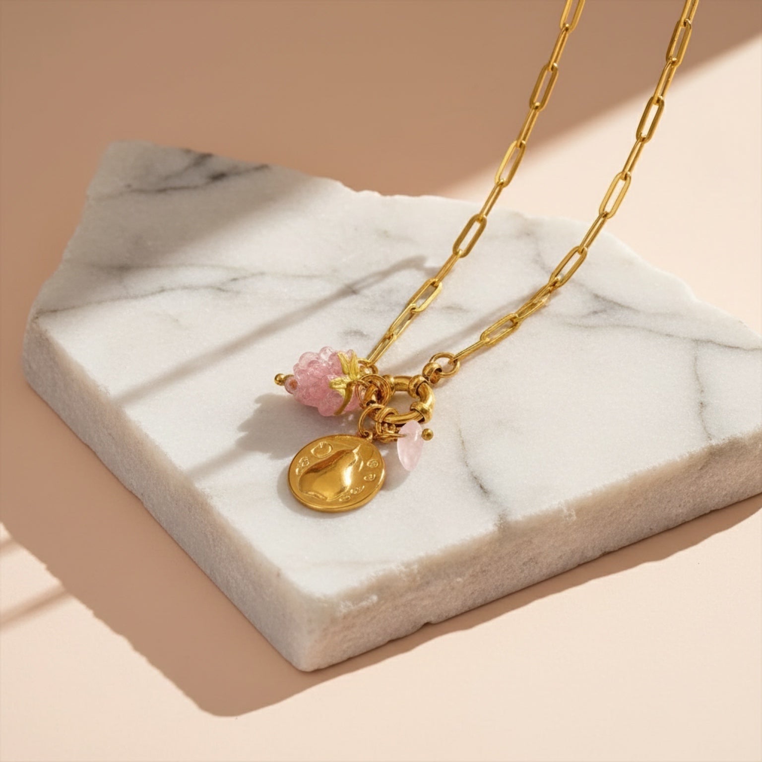 Chévereh Pinky Charm Necklace with gold chain, pink berry charm, gold coin, and rose quartz stone.