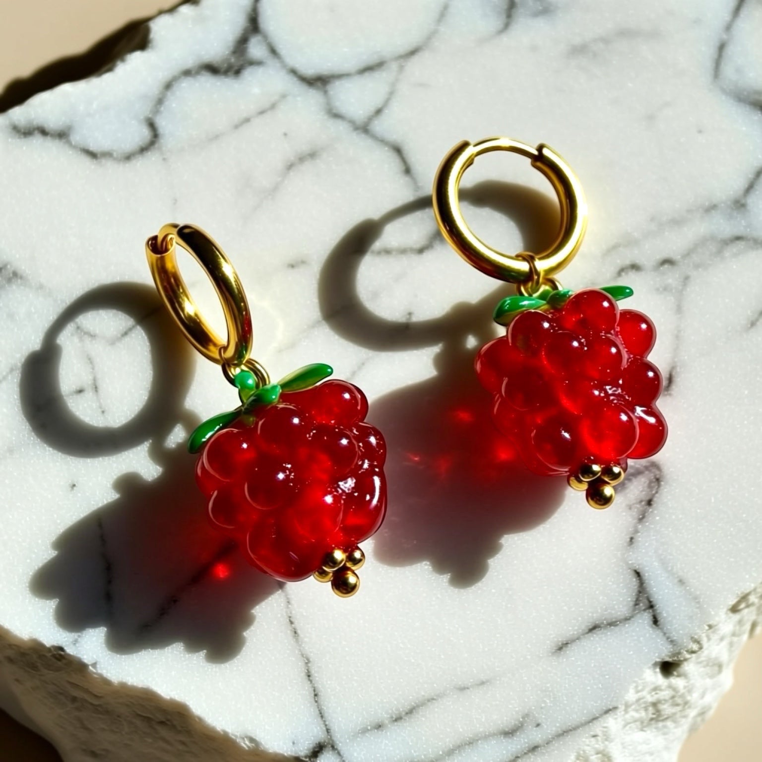 Chévereh Raspberry Glass Drop Earrings with gold hoops, red glass beads, green leaf accents, and gold bead details.