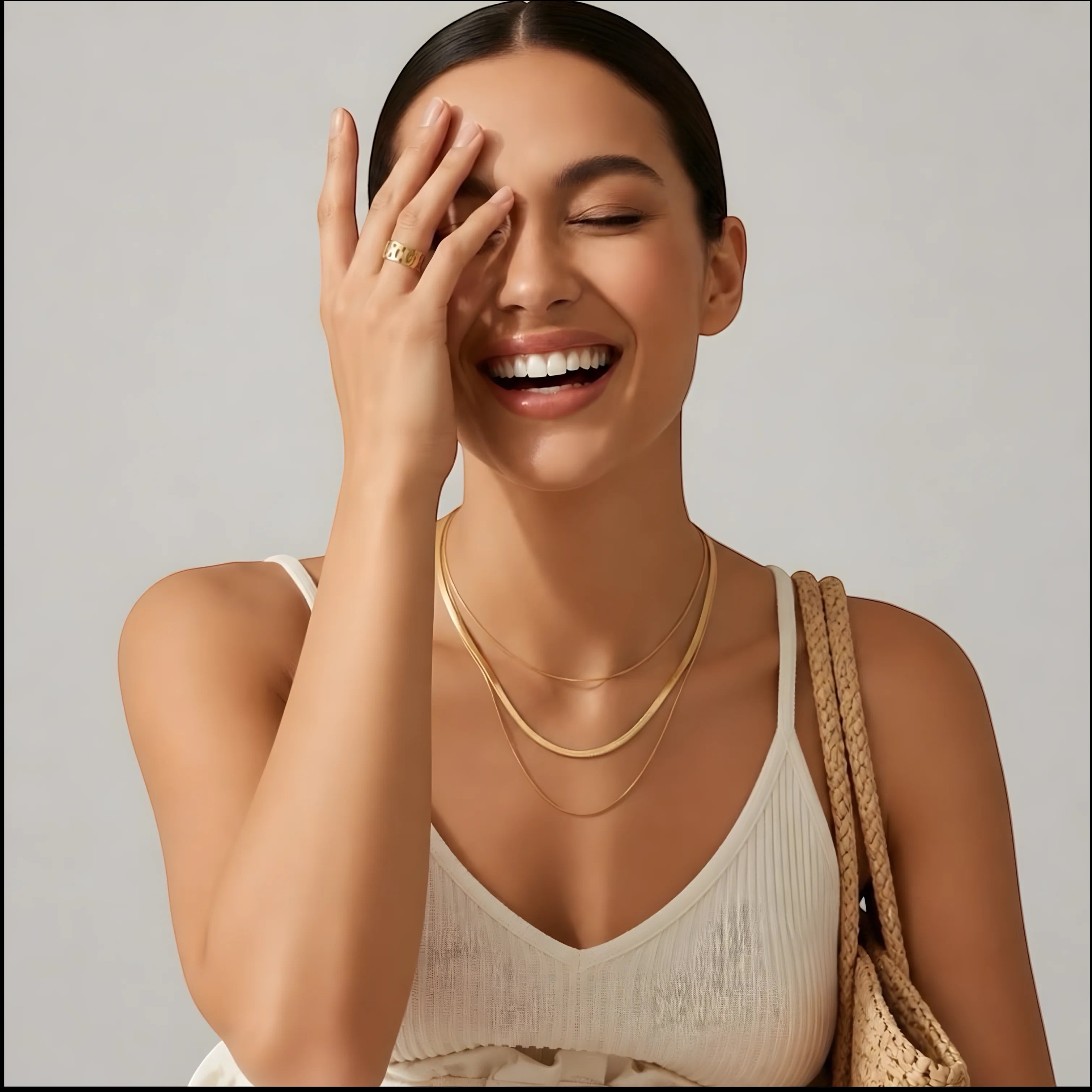 A smiling woman wearing a Chévereh three-layer gold-tone chain necklace with a white ribbed tank top.