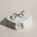 Chévereh White Bloom & Gold flower drop-style hoop earrings with translucent white charms and gold hoops.